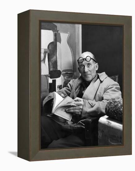 Architect Le Corbusier Sitting in Chair and Holding Book in Hands-Nina Leen-Framed Premier Image Canvas