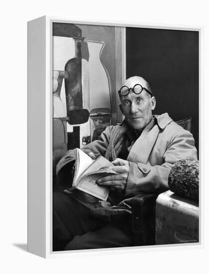 Architect Le Corbusier Sitting in Chair and Holding Book in Hands-Nina Leen-Framed Premier Image Canvas