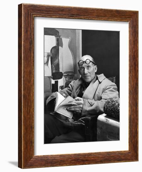 Architect Le Corbusier Sitting in Chair and Holding Book in Hands-Nina Leen-Framed Premium Photographic Print