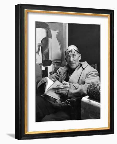 Architect Le Corbusier Sitting in Chair and Holding Book in Hands-Nina Leen-Framed Premium Photographic Print