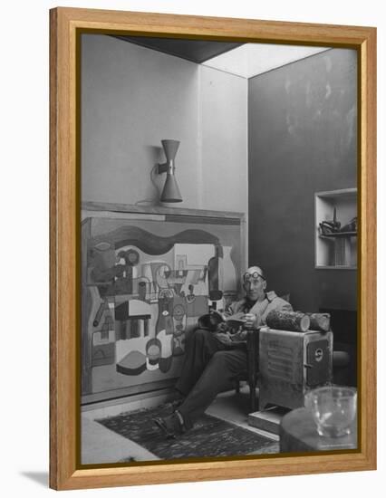 Architect Le Corbusier Sitting in Chair with Book in Hands, Glasses Perched on His Forehead-Nina Leen-Framed Premier Image Canvas