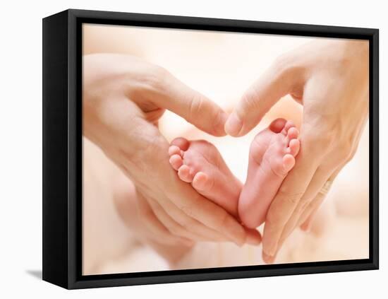 Baby Feet in Mother Hands. Tiny Newborn Baby's Feet on Female Heart Shaped Hands Closeup. Mom and H-Subbotina Anna-Framed Premier Image Canvas