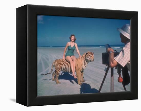 Bathing Beauty Sitting on Back of Large Tiger on Beach as Photographer Sets Up Camera-Eliot Elisofon-Framed Premier Image Canvas