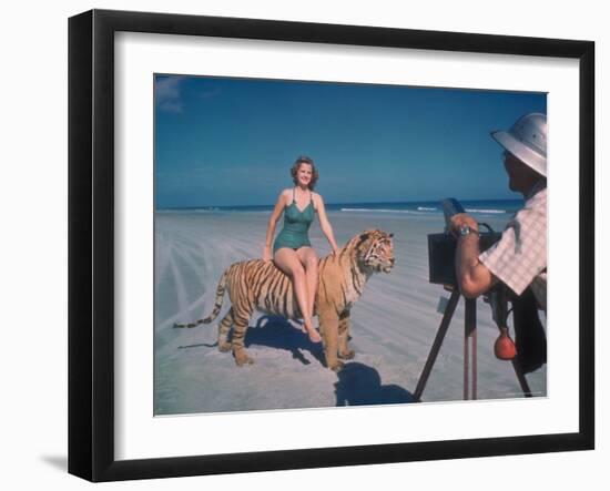 Bathing Beauty Sitting on Back of Large Tiger on Beach as Photographer Sets Up Camera-Eliot Elisofon-Framed Photographic Print