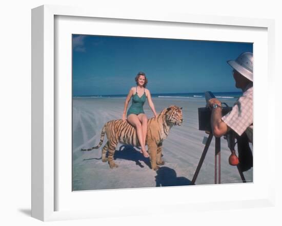 Bathing Beauty Sitting on Back of Large Tiger on Beach as Photographer Sets Up Camera-Eliot Elisofon-Framed Photographic Print