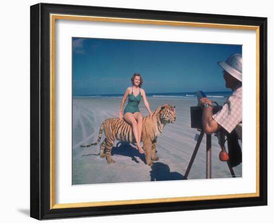 Bathing Beauty Sitting on Back of Large Tiger on Beach as Photographer Sets Up Camera-Eliot Elisofon-Framed Photographic Print