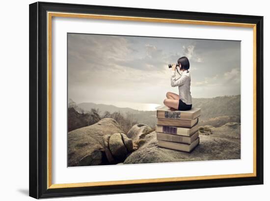 Beautiful Woman Sitting On A Pile Of Old Books Watching With Binoculars-olly2-Framed Art Print