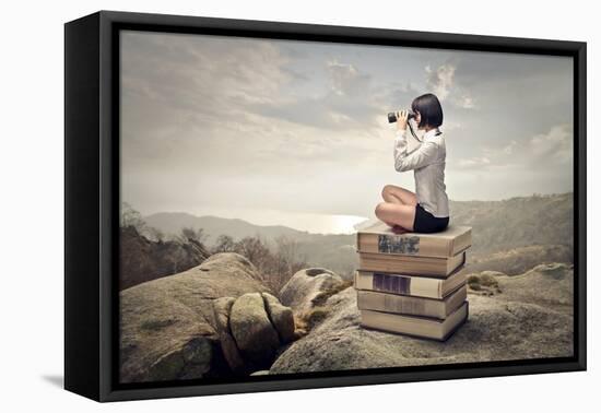 Beautiful Woman Sitting On A Pile Of Old Books Watching With Binoculars-olly2-Framed Stretched Canvas