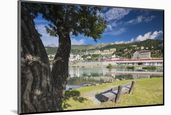 Bernina Express train runs past the village of St. Moritz surrounded by lake, Canton of Graubunden,-Roberto Moiola-Mounted Photographic Print