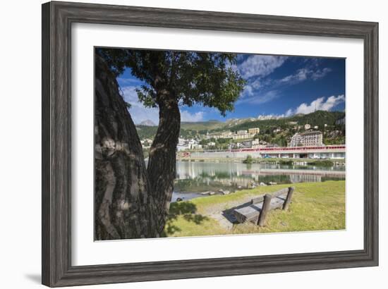 Bernina Express train runs past the village of St. Moritz surrounded by lake, Canton of Graubunden,-Roberto Moiola-Framed Photographic Print