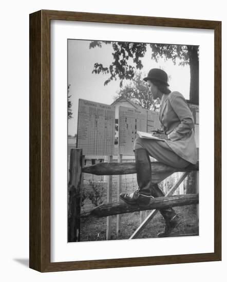 Betty Jane Baldwin Sitting on Fence and Looking at Official Board at Warrenton Horse Show-Martha Holmes-Framed Photographic Print