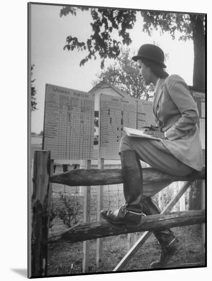 Betty Jane Baldwin Sitting on Fence and Looking at Official Board at Warrenton Horse Show-Martha Holmes-Mounted Photographic Print