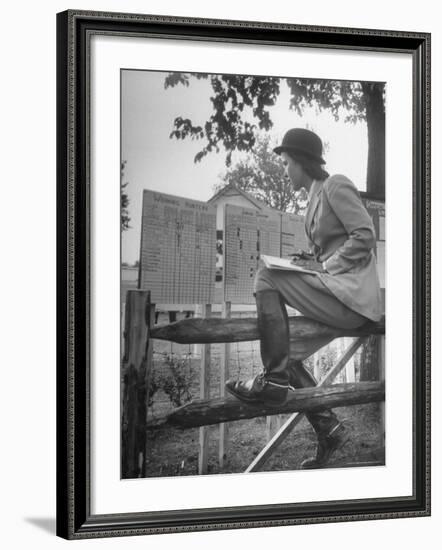 Betty Jane Baldwin Sitting on Fence and Looking at Official Board at Warrenton Horse Show-Martha Holmes-Framed Photographic Print