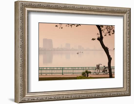 Bicycle parked at the lakeside with city skyline in the background, West Lake, Tay Ho, Hanoi, Vi...-null-Framed Photographic Print