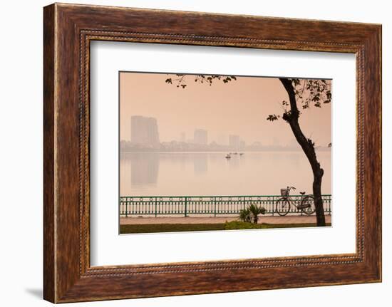 Bicycle parked at the lakeside with city skyline in the background, West Lake, Tay Ho, Hanoi, Vi...-null-Framed Photographic Print