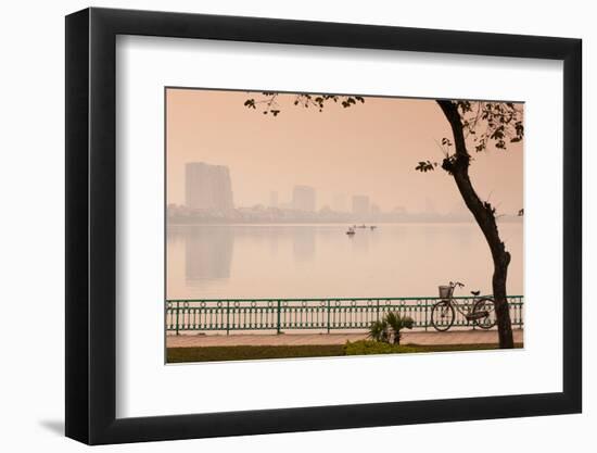 Bicycle parked at the lakeside with city skyline in the background, West Lake, Tay Ho, Hanoi, Vi...-null-Framed Photographic Print