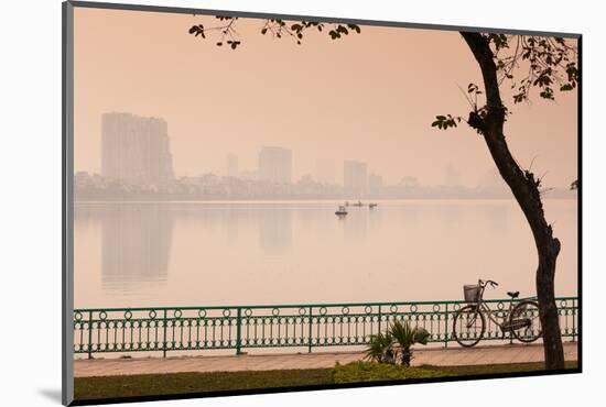 Bicycle parked at the lakeside with city skyline in the background, West Lake, Tay Ho, Hanoi, Vi...-null-Mounted Photographic Print