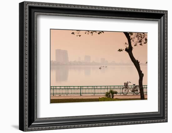 Bicycle parked at the lakeside with city skyline in the background, West Lake, Tay Ho, Hanoi, Vi...-null-Framed Photographic Print