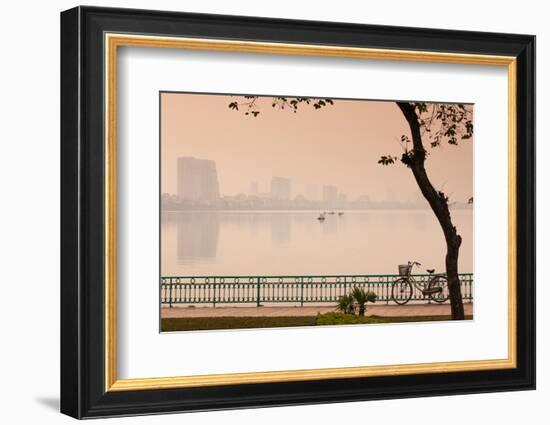 Bicycle parked at the lakeside with city skyline in the background, West Lake, Tay Ho, Hanoi, Vi...-null-Framed Photographic Print