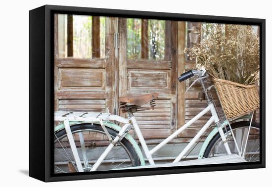 Bicycle with a Basket of a Dried Bouquet Flower Stand in Front of Wooden and Rustic House Backgroun-WichitS-Framed Premier Image Canvas