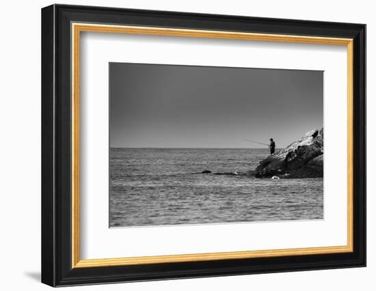 Black and White shot of a lone fisherman on rocks at the beach-null-Framed Photo