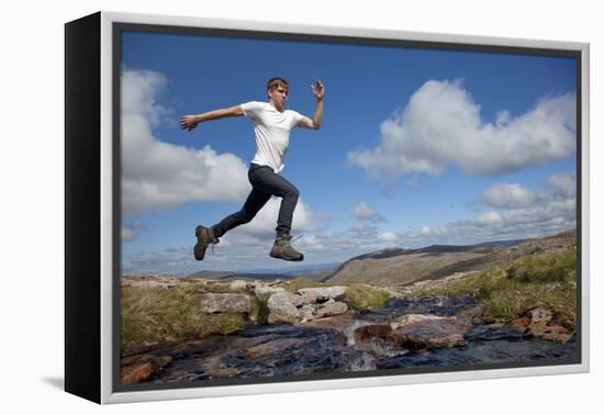 Boy (Aged 17) Jumping across Upland Stream-Mark Hamblin-Framed Premier Image Canvas