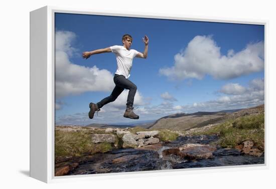 Boy (Aged 17) Jumping across Upland Stream-Mark Hamblin-Framed Premier Image Canvas