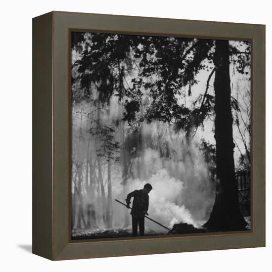 Boy Combining Play and Seasonal Chore, Stirring a Pile of Burning Leaves-Allan Grant-Framed Premier Image Canvas