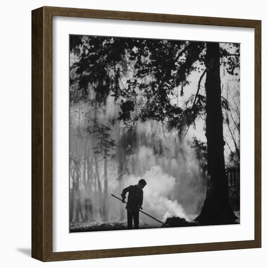 Boy Combining Play and Seasonal Chore, Stirring a Pile of Burning Leaves-Allan Grant-Framed Photographic Print