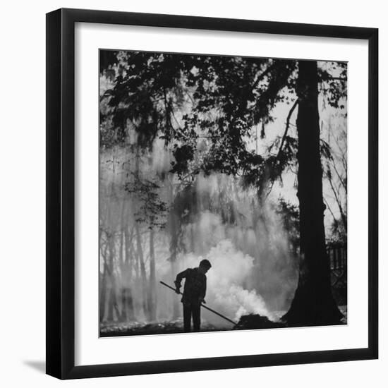 Boy Combining Play and Seasonal Chore, Stirring a Pile of Burning Leaves-Allan Grant-Framed Photographic Print