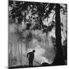 Boy Combining Play and Seasonal Chore, Stirring a Pile of Burning Leaves-Allan Grant-Mounted Photographic Print