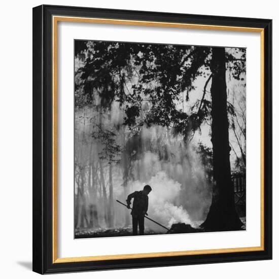 Boy Combining Play and Seasonal Chore, Stirring a Pile of Burning Leaves-Allan Grant-Framed Photographic Print