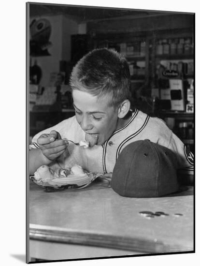 Boy Wearing Baseball Uniform Eating Banana Split at Soda Fountain Counter-Joe Scherschel-Mounted Photographic Print