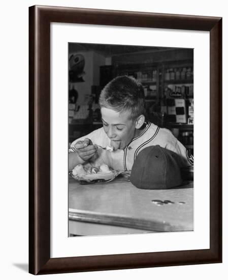 Boy Wearing Baseball Uniform Eating Banana Split at Soda Fountain Counter-Joe Scherschel-Framed Photographic Print