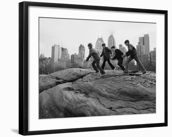 Boys Climbing About on Rock Formation in Central Park as Essex House Looms Amidst Skyline of City-Bill Ray-Framed Photographic Print