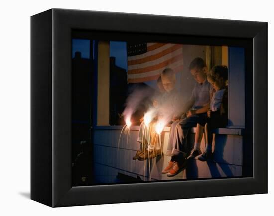 Boys Sitting on Porch Holding Sparklers, with US Flag in Back, During Independence Day Celebration-Nat Farbman-Framed Premier Image Canvas