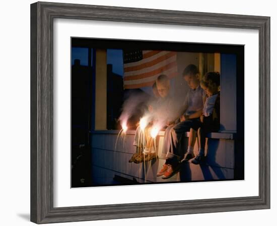 Boys Sitting on Porch Holding Sparklers, with US Flag in Back, During Independence Day Celebration-Nat Farbman-Framed Photographic Print