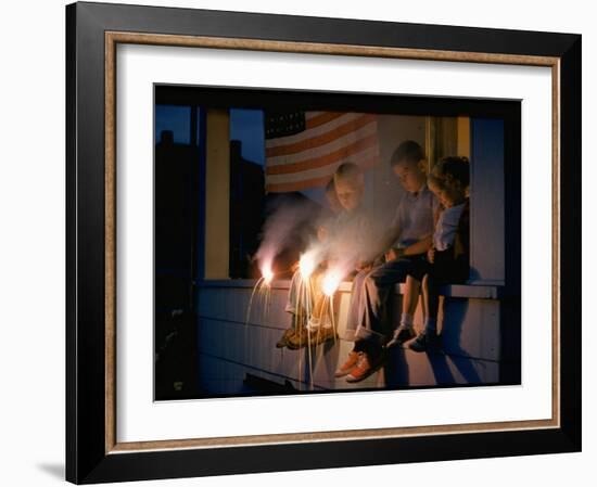 Boys Sitting on Porch Holding Sparklers, with US Flag in Back, During Independence Day Celebration-Nat Farbman-Framed Photographic Print