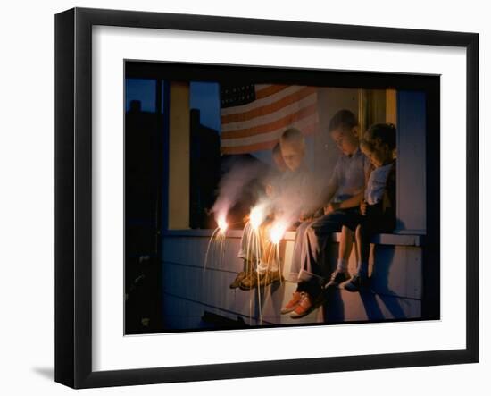 Boys Sitting on Porch Holding Sparklers, with US Flag in Back, During Independence Day Celebration-Nat Farbman-Framed Photographic Print