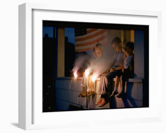 Boys Sitting on Porch Holding Sparklers, with US Flag in Back, During Independence Day Celebration-Nat Farbman-Framed Photographic Print