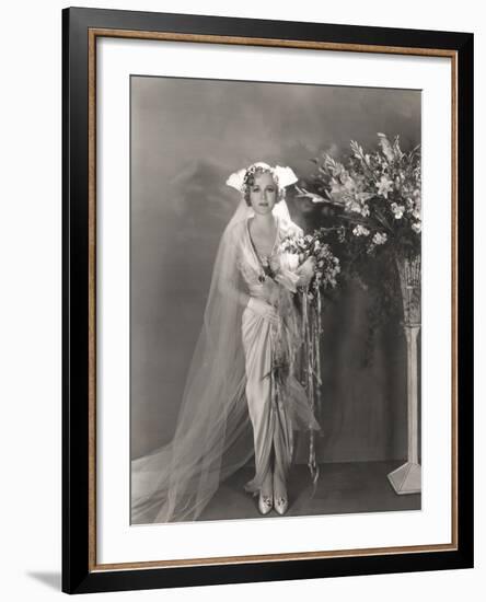 Bride Standing Next to Tall Vase of Flowers-null-Framed Photo