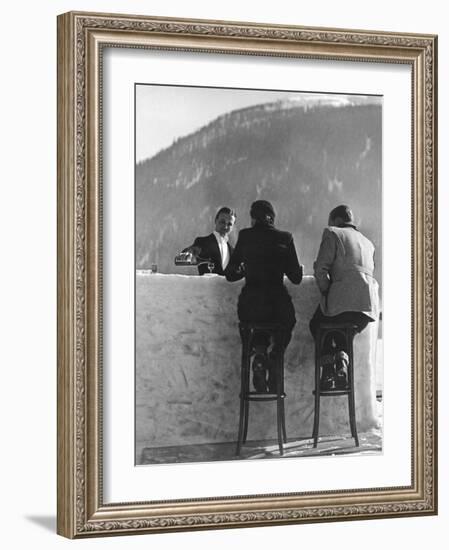 British Couple on High Stools at Ice Bar Outdoors at Grand Hotel as Waiter Pours Them Drinks-Alfred Eisenstaedt-Framed Photographic Print