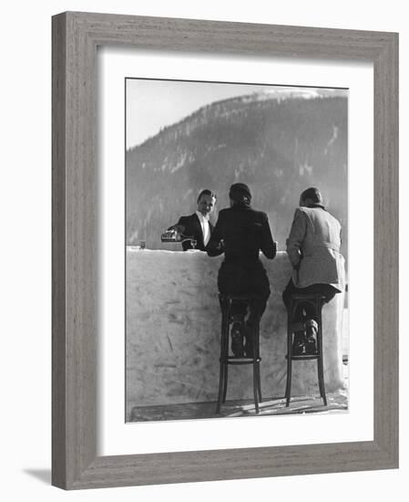 British Couple on High Stools at Ice Bar Outdoors at Grand Hotel as Waiter Pours Them Drinks-Alfred Eisenstaedt-Framed Photographic Print