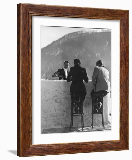 British Couple on High Stools at Ice Bar Outdoors at Grand Hotel as Waiter Pours Them Drinks-Alfred Eisenstaedt-Framed Photographic Print