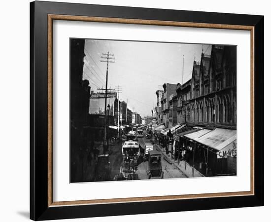 Bustling View of Fulton St, with Rows of Shops and Horse Drawn Carriages-Wallace G^ Levison-Framed Photographic Print