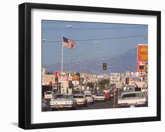 Cars Moving Along Congested Street, Littered with Signs, Billboards and Traffic Directives-Michael Rougier-Framed Photographic Print