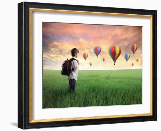 Child Carrying A Backpack Standing On A Green Meadow With Hot-Air Balloons In The Background-olly2-Framed Art Print