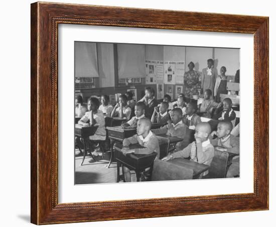 Children Sitting at their Desks in a Classroom, Teachers at the Rear of the Room-null-Framed Photographic Print