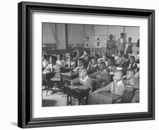 Children Sitting at their Desks in a Classroom, Teachers at the Rear of the Room-null-Framed Photographic Print