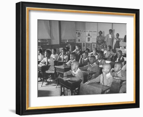 Children Sitting at their Desks in a Classroom, Teachers at the Rear of the Room-null-Framed Photographic Print